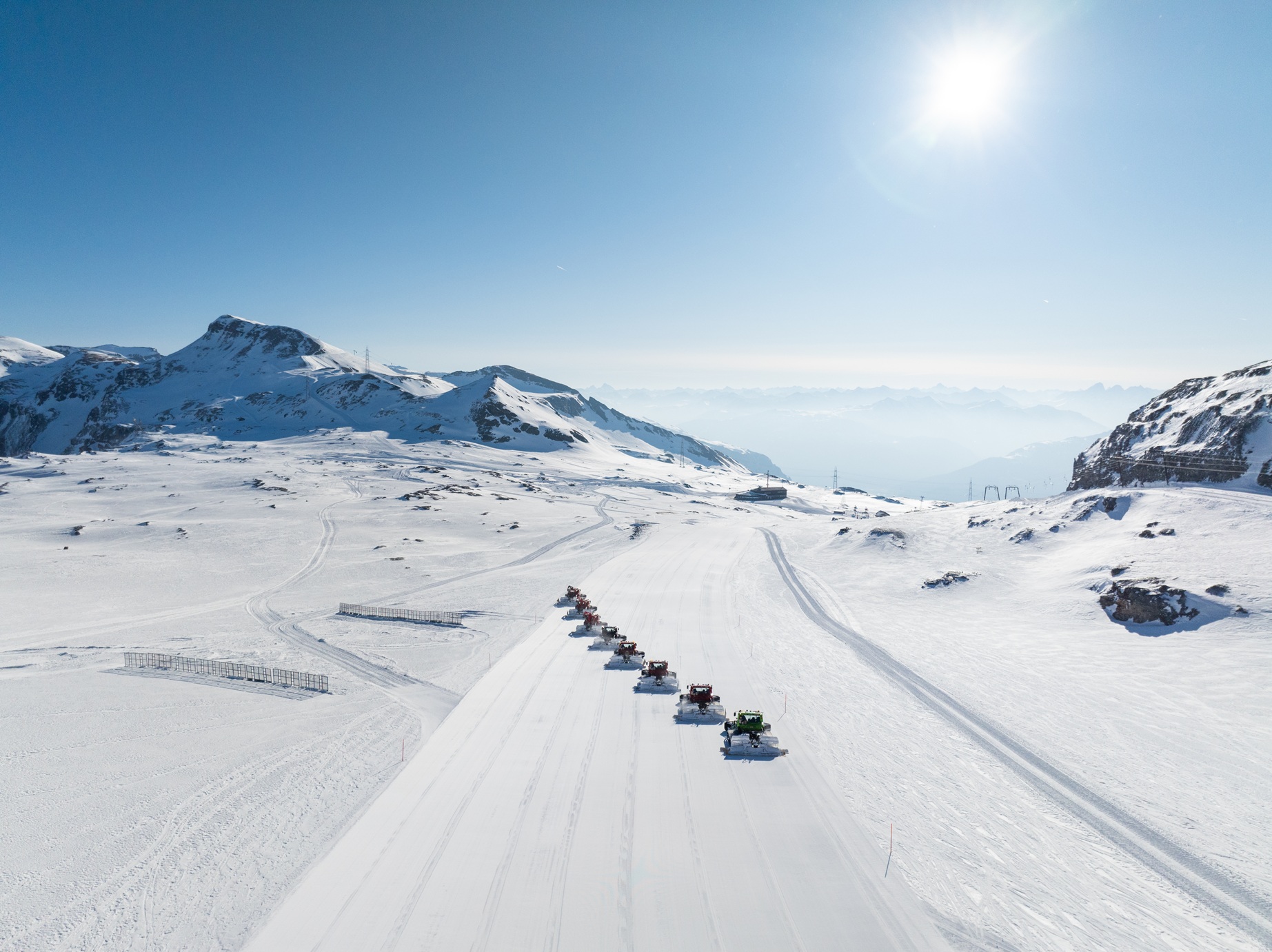 Weite Schneefläche mit gezogener Loipe vor Bergpanorama
